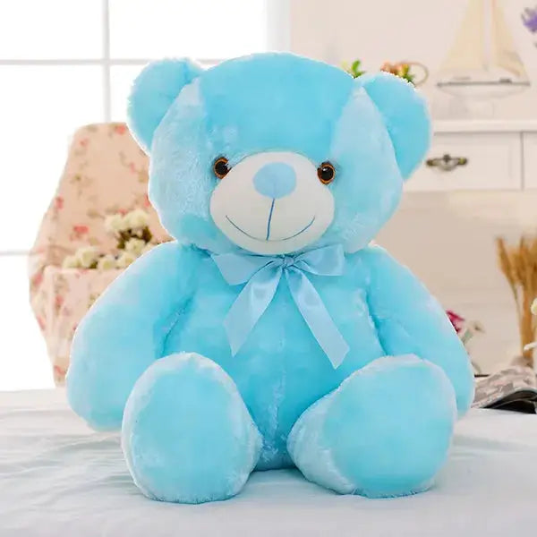 a blue teddy bear sitting on top of a bed