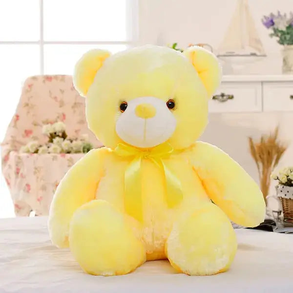 a yellow teddy bear sitting on top of a bed