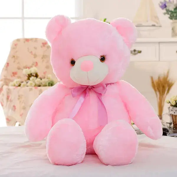 a pink teddy bear sitting on top of a bed