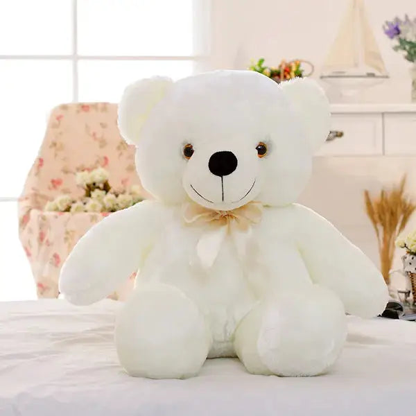 a white teddy bear sitting on top of a bed