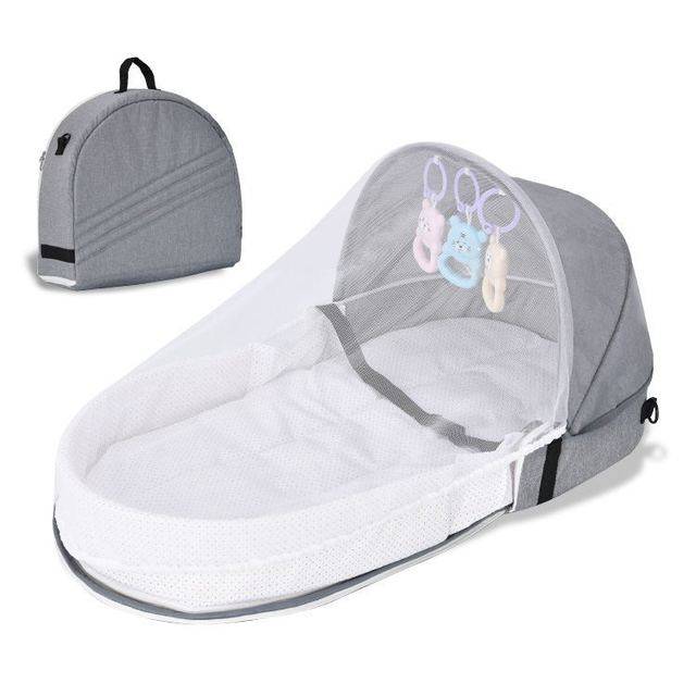 a grey and white baby crib with a bag