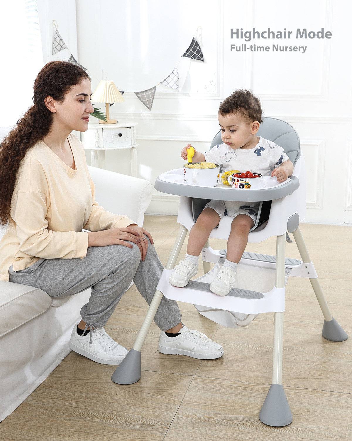 a woman sitting next to a baby in a high chair