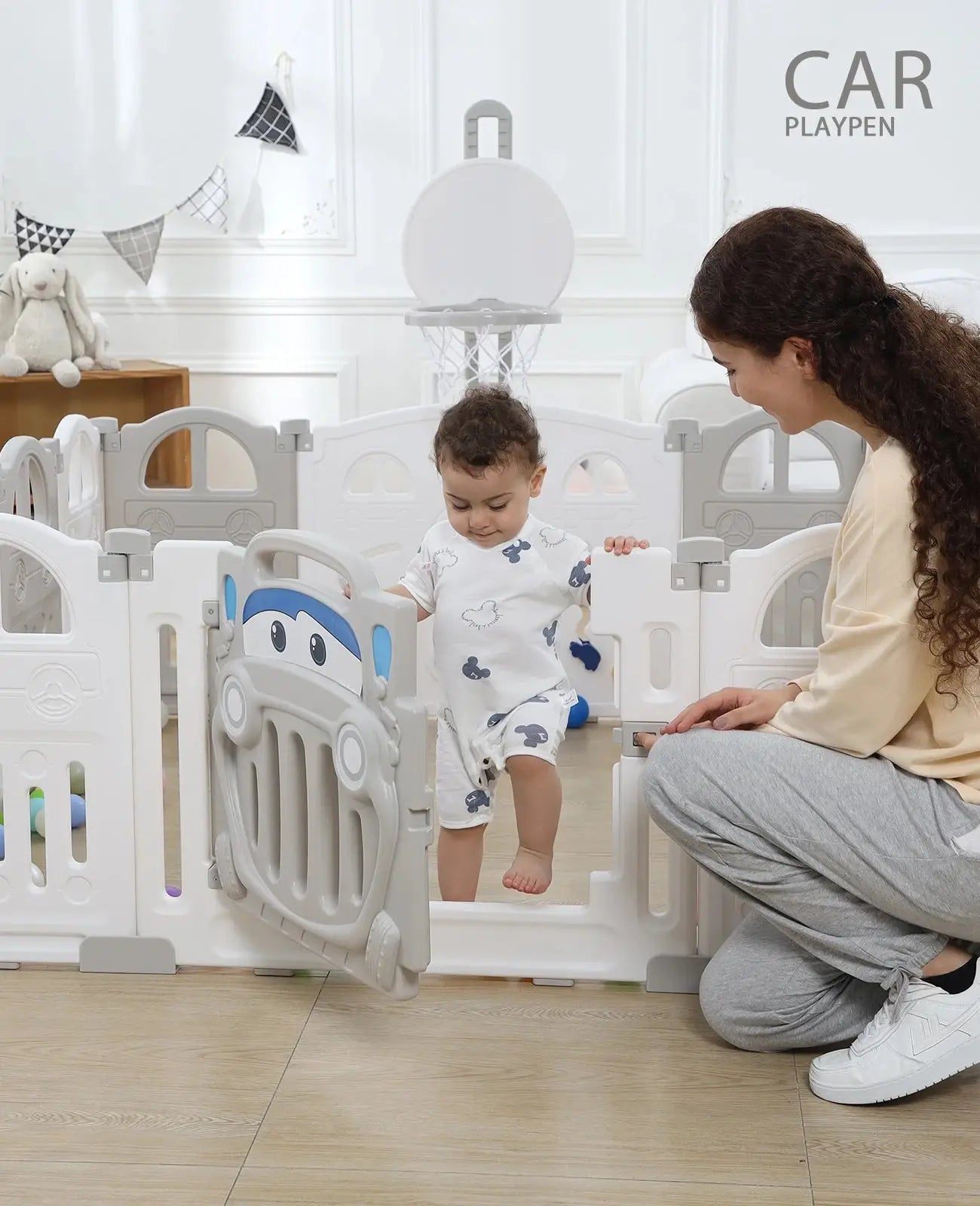 a woman kneeling down next to a baby in a playpen